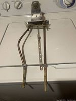 Top view of metal faucet with two bent copper-like supply lines and mounting bracket, showing aged and worn condition.