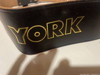 Close-up of the York logo printed in gold on the black leather belt material.