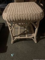 Side view of wicker side table showing woven wicker frame, legs, and lower shelf detail.