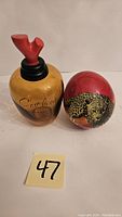 Front view of empty C'est la Vie! bottle with red stopper and glass leopard egg showing detailed leopard pattern
