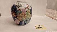 Front and side views of a hand painted Chinese porcelain vase with floral motifs in multiple colors including blue, green, pink, yellow, and red.