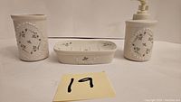 Front view of Lenox Rose Manor bathroom set including cup, soap dish and soap pump in cream with gray floral pattern