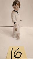 Front view of Rex porcelain girl figurine showing detailed facial features and white dress with black trim and gold object