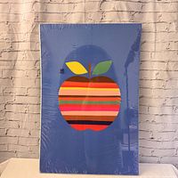 Full view of apple print sealed in plastic wrap against a brick wall background