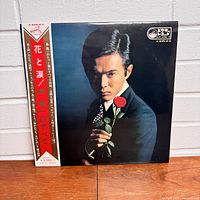 Front of vinyl album with color photo of Mori Shinichi holding a red rose and paper obi strip with Japanese text