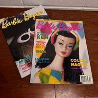 Two vintage Barbie Bazaar magazines, one featuring Barbie in yellow and green outfit, the other with Barbie wearing cat-eye sunglasses.