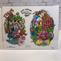 Full laminated tattoo flash art sheet showing two colorful tattoo designs including a waterfall scene with bridge, dragonflies, and flowers, and a bee on a flower with foliage.