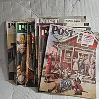 Photo showing a stack of eight Saturday Evening Post magazines with illustrated 1950s style covers including a rural gas station scene.