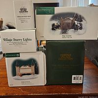 Five Department 56 boxes displayed showing different village accessory items included in the lot.