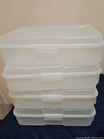 Stack of four clear plastic storage totes with snap-on lids.