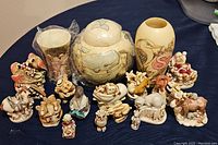 Full lot view showing all 17 ceramic Harmony Garden figurines and vases on a blue cloth surface.