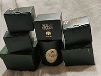 Seven green boxes of various sizes with Harmony Kingdom and Netsuke branding, some stacked.