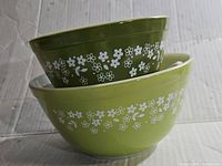 Two stacked Pyrex Crazy Daisy mixing bowls showing green exterior with white floral pattern.