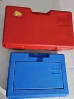 Two LEGO cases stacked, red on top and blue on bottom, showing external design and LEGO logo.