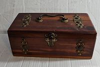 Front and top view of the vintage Pilliod wooden art box showing wood grain, metal studs, latch and handle.