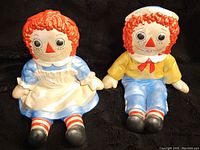 Front view showing both Raggedy Anne and Andy figurines sitting side by side, capturing their detailed costumes and facial features.