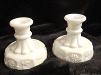Pair of Westmoreland milk glass candle holders showing full side and top views, highlighting grapevine embossed pattern.