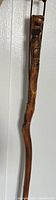Full view of the carved wooden cane showing detailed carvings near the handle area.