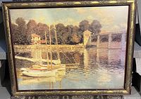Framed Claude Monet print showing sailboats docked along a river with buildings and a bridge.