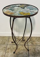 Full view of the embossed butterfly accent table showing round glass top and curved metal legs.