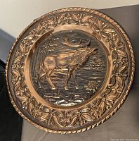 Top view of the embossed copper wall plate showing detailed deer design and floral border.