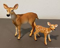 Photo showing the Schleich doe and fawn figurines placed side by side on a flat surface against a plain background.