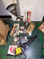 Overview of all items including DeWalt sander, Delta sliding miter jig, woodworking templates, sanding discs, and assorted accessories spread on green floor against white wall.