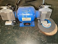 Full view of the Power Glide bench grinder showing both grinding wheels, safety shields, and grinding pads included.