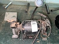 Full view of bench grinder showing abrasive wheel, wire brush wheel, and attached adjustable light.