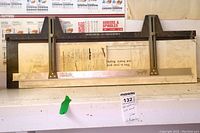 Full view of the 32-inch Leochtung mat cutting guide showing the wooden base, metal measuring bar, adjustable sliding brackets, and attached instructions.