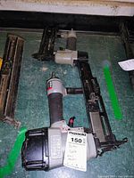 Two Porter Cable pneumatic nail machines lying on a green surface, showing full length and parts.