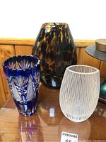 Three glass vases displayed together on a wooden surface showing relative sizes and colors.