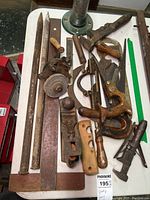 Overview photo showing assortment of vintage hand tools including saws, hand planes, and wrenches on a white table.