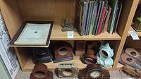 Overview of horology books on top shelf and assorted clock casings on lower shelf