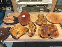 Nine burl wood clock faces arranged on a table with natural shapes and clock numerals.