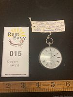 Antique sterling silver pocket watch by G. Barham & Son, with the tag showing maker and date (circa 1880) and a ruler for scale