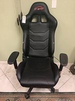 Front view of black Top Gamer gaming chair showing seat, armrests, and base with wheels.