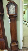 Full front view of oak granddaughter clock with arched top and long case