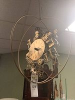 Clock suspended by wire showing full spherical frame and central clock face.