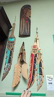 Overview of all five wall hangings (one mask, four feather plaques) mounted on wall