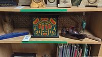 Three items on shelf: painted box center, bird container right, turquoise bird left