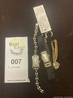 Overview of three watches on black background with lot tag