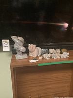 Full set of ten animal sculptures arranged on a wooden surface including soapstone bears and jade otter.