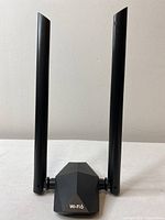 Front view of AX1800 Wi-Fi 6 USB adapter showing geometric design and dual high-gain antennas.