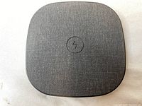 Top view of black wireless charging pad with fabric surface and wireless charging icon center.