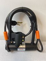 Front view of Sigtuna heavy duty black U-lock bike lock with attached cable and two keys inserted in the cylinder.