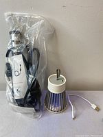 Mosquito lamp with USB cable and immersion water heater wrapped in clear plastic.