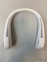 Front view of the white neck fan showing symmetrical air vents and overall horseshoe shape.