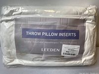 Photo showing one Leeden throw pillow insert in clear packaging with label stating durability, breathability, hypoallergenic and machine washable features.