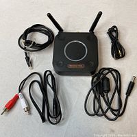 1Mii B06 Pro audio adapter with two antennas surrounded by included cables: RCA, auxiliary, power, and ethernet cables laid around the adapter.